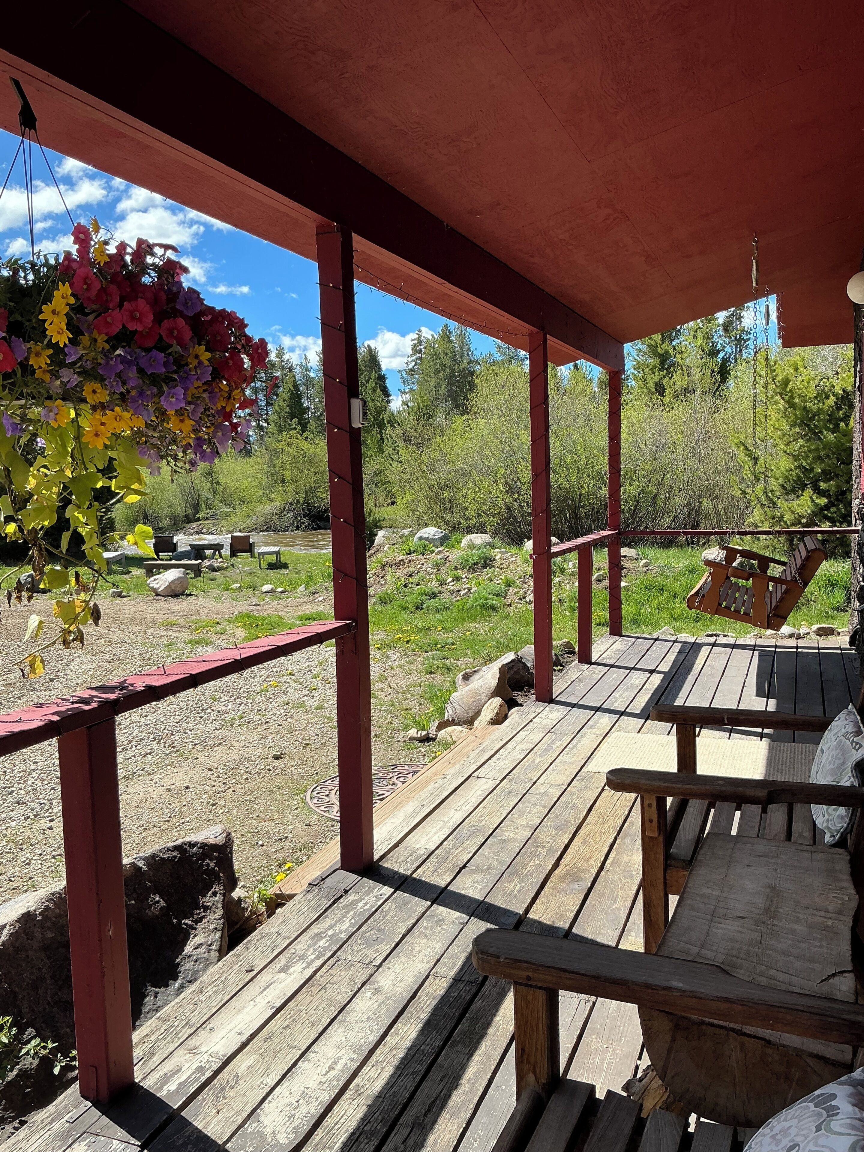 A covered outdoor area with wooden benches and a hanging flower arrangement.