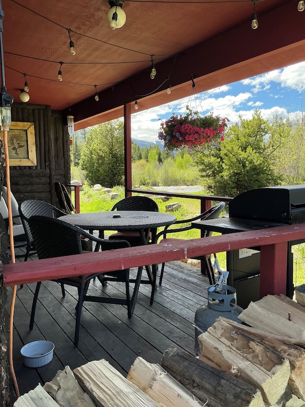 Une terrasse en bois avec des meubles d’extérieur, un barbecue et une jardinière suspendue.