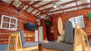 A log cabin interior with wooden furniture, a television, and a large wooden door.