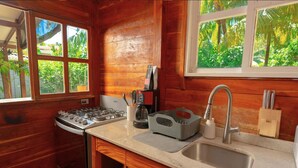 A compact kitchen with a gas stove, a sink, and wooden walls.