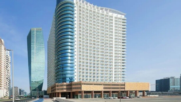 Un hotel moderno con facciata curva, diversi piani e un ingresso ben visibile.