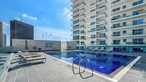 Una piscina sul tetto con lettini e un grattacielo sullo sfondo.