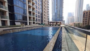 Una piscina sul tetto con ringhiera in vetro, circondata da edifici residenziali a grattacielo.