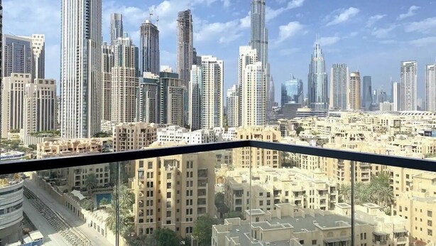 Paesaggio urbano con edifici alti, tra cui un grattacielo ben visibile, ammirato da un balcone.