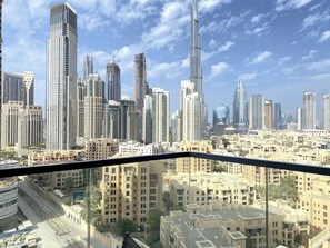 A cityscape with high-rise buildings, including a prominent skyscraper, viewed from a balcony. - 1BR with Iconic Burj View | Free Airport pick-up (Dubai)