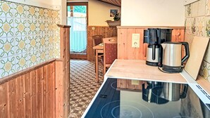 A compact kitchen with a wooden countertop, a stove, and a coffee maker.