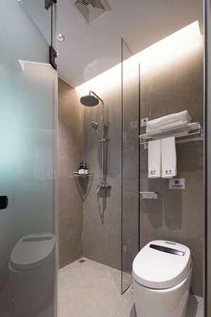 A modern bathroom with a glass-enclosed shower, a white toilet, and a towel rack with folded towels. - Colorstory Hotel (Hangzhou)