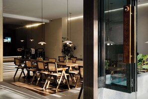 A modern dining area with wooden furniture and pendant lighting. - Colorstory Hotel (Hangzhou)