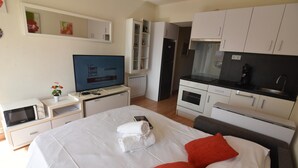 A hotel room with a bed, a TV, a microwave, a small kitchenette, and a bathroom. - Discover this charming studio in Santa Margarita, Roses! (Roses)