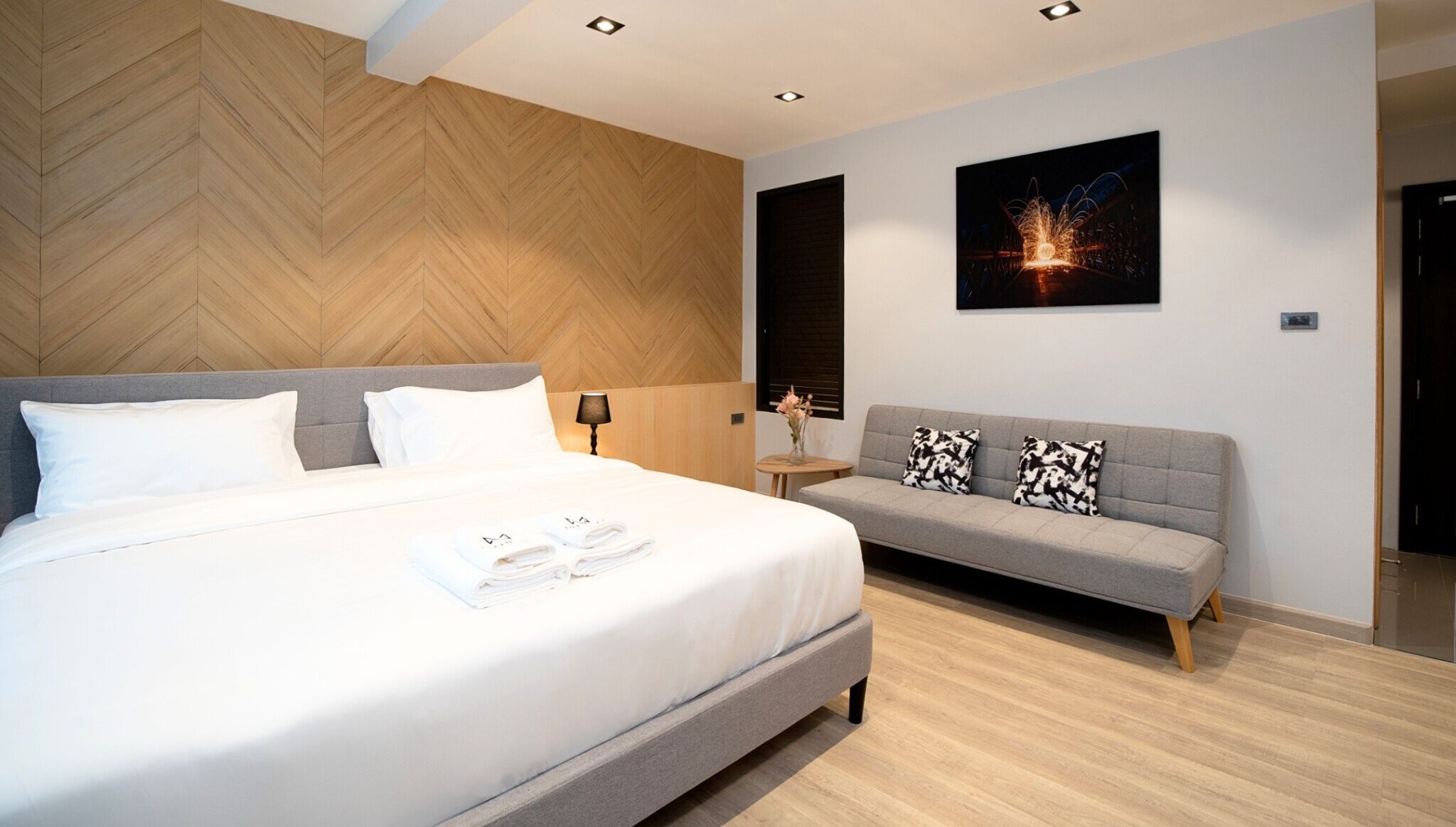 Une chambre d’hôtel moderne, dotée d’un grand lit, d’un canapé, d’une table de chevet et d’un tableau accroché au mur.