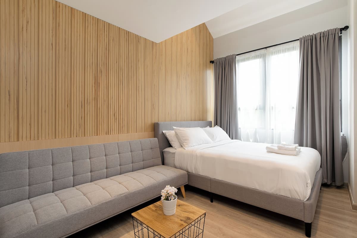 Een moderne hotelkamer met een bank, een bed en een houten accentmuur.