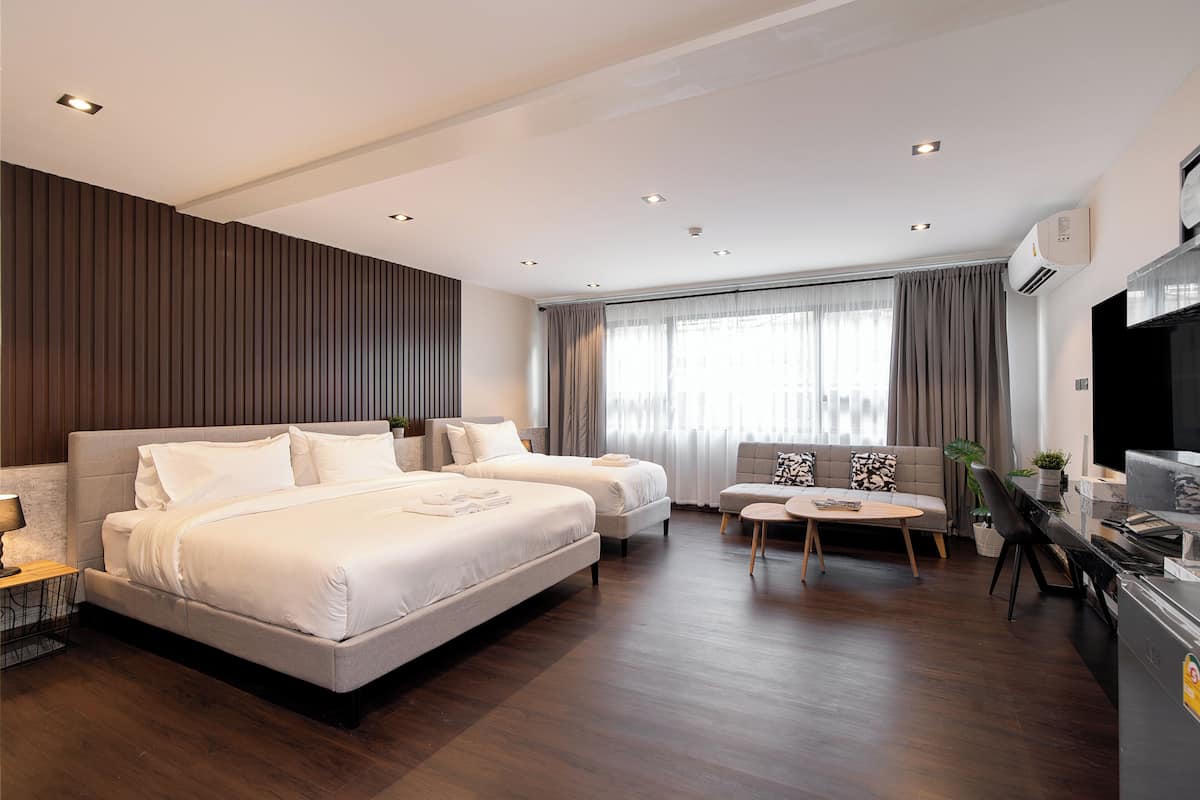Een moderne hotelkamer met een groot bed, twee banken, een eettafel en een televisie.