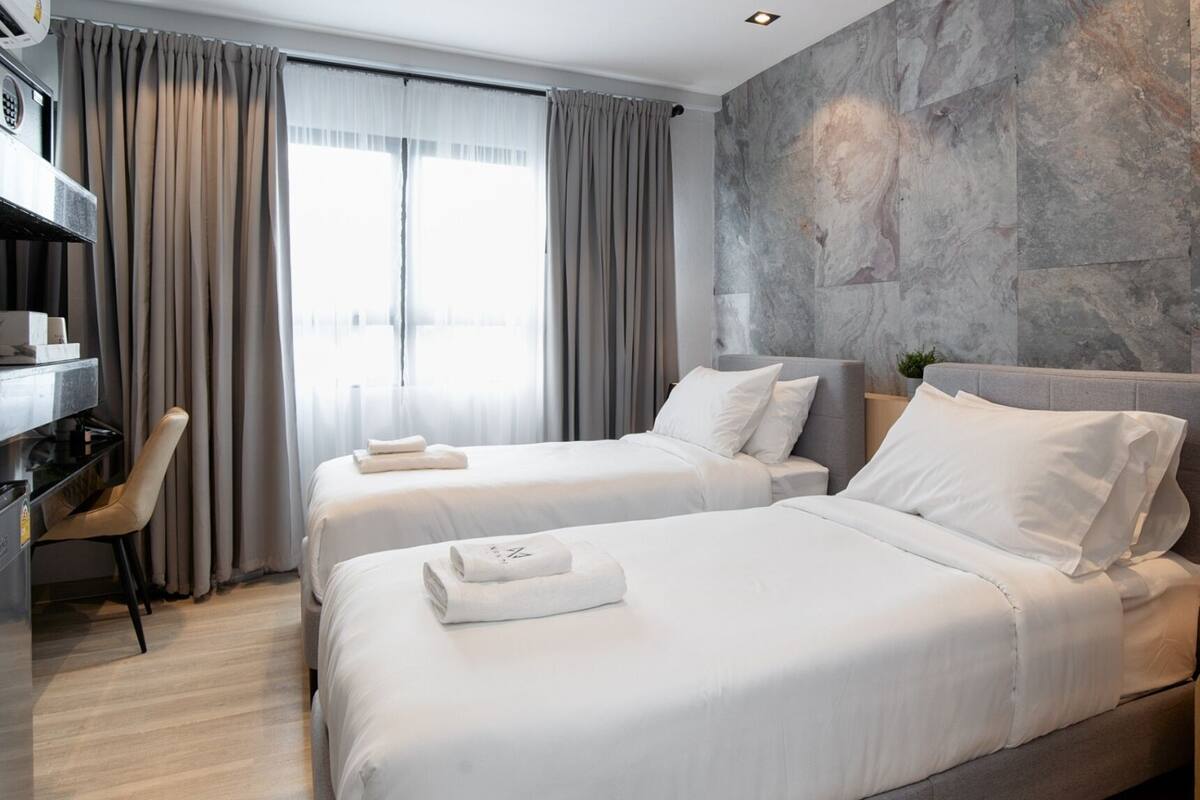 Een hotelkamer met twee bedden, een bureau en een stoel.