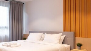 A modern bedroom with a grey bed, white linens, a wooden headboard, and a small bedside table with a plant. - Infinite Hotel Kaset-Senanikom (Bangkok)