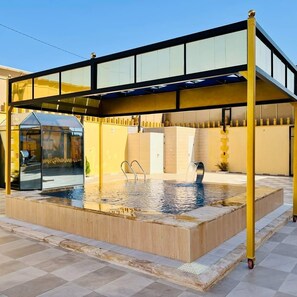 A swimming pool with a glass enclosure, a covered seating area, and a water feature. - Kareem resort (Ramtha)