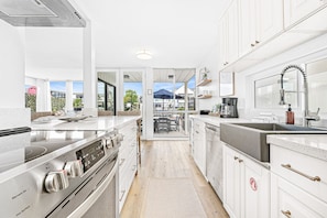 A modern kitchen with stainless steel appliances, white cabinetry, and a view to the outside.