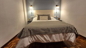 A narrow room with a bed, two bedside lamps, a patterned pillow, and a striped bedspread. - 655A El Rincón del Riego (Oviedo)