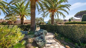 A stone pathway leading through a garden with palm trees and various shrubs. - El Cantarello by Interhome (Sainte Maxime)