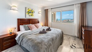 A hotel room with a large bed, a nightstand, a lamp, a painting, and a window with a view. - Marvelous views, pools, steps to the beach! REF024 (Benalmádena)