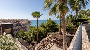 A coastal building with balconies overlooking the sea, surrounded by palm trees and a landscaped garden. - Marvelous views, pools, steps to the beach! REF024 (Benalmádena)