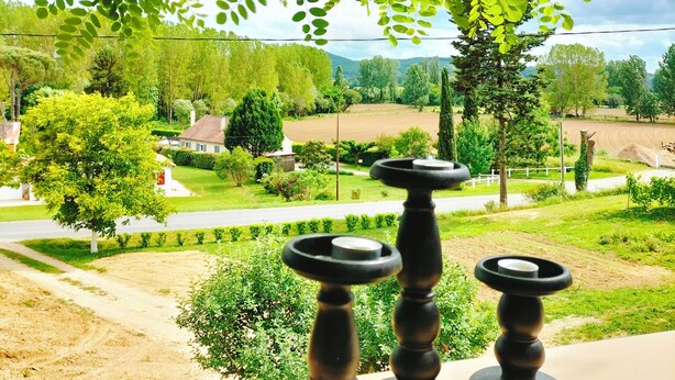 Vista a través de una ventana con una mesa que tiene tres candelabros negros.