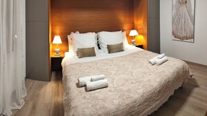 Una cama bien hecha con un edredón estampado, dos almohadas y dos lámparas de noche.