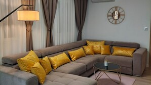 Una sala de estar moderna con un sofá modular, una mesa de centro redonda y una lámpara de pie.