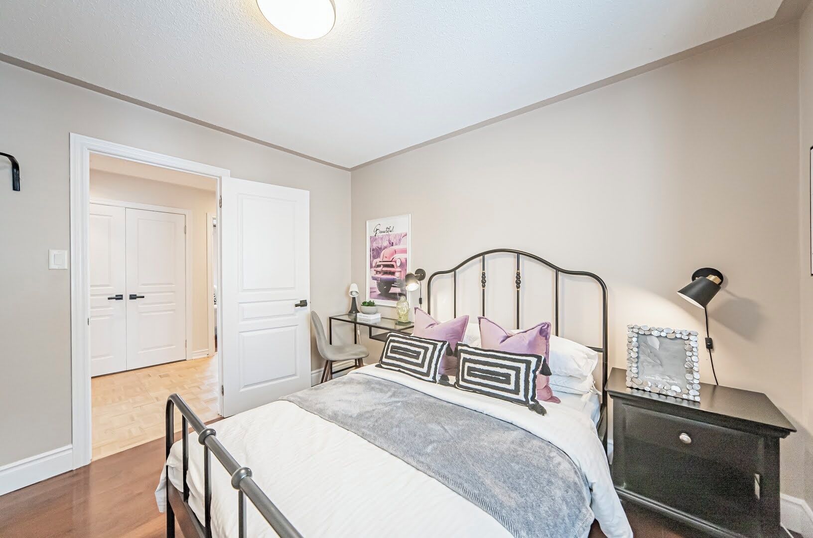 Une chambre à coucher comprenant un lit, une table de chevet, une lampe et une porte donnant sur une autre pièce.