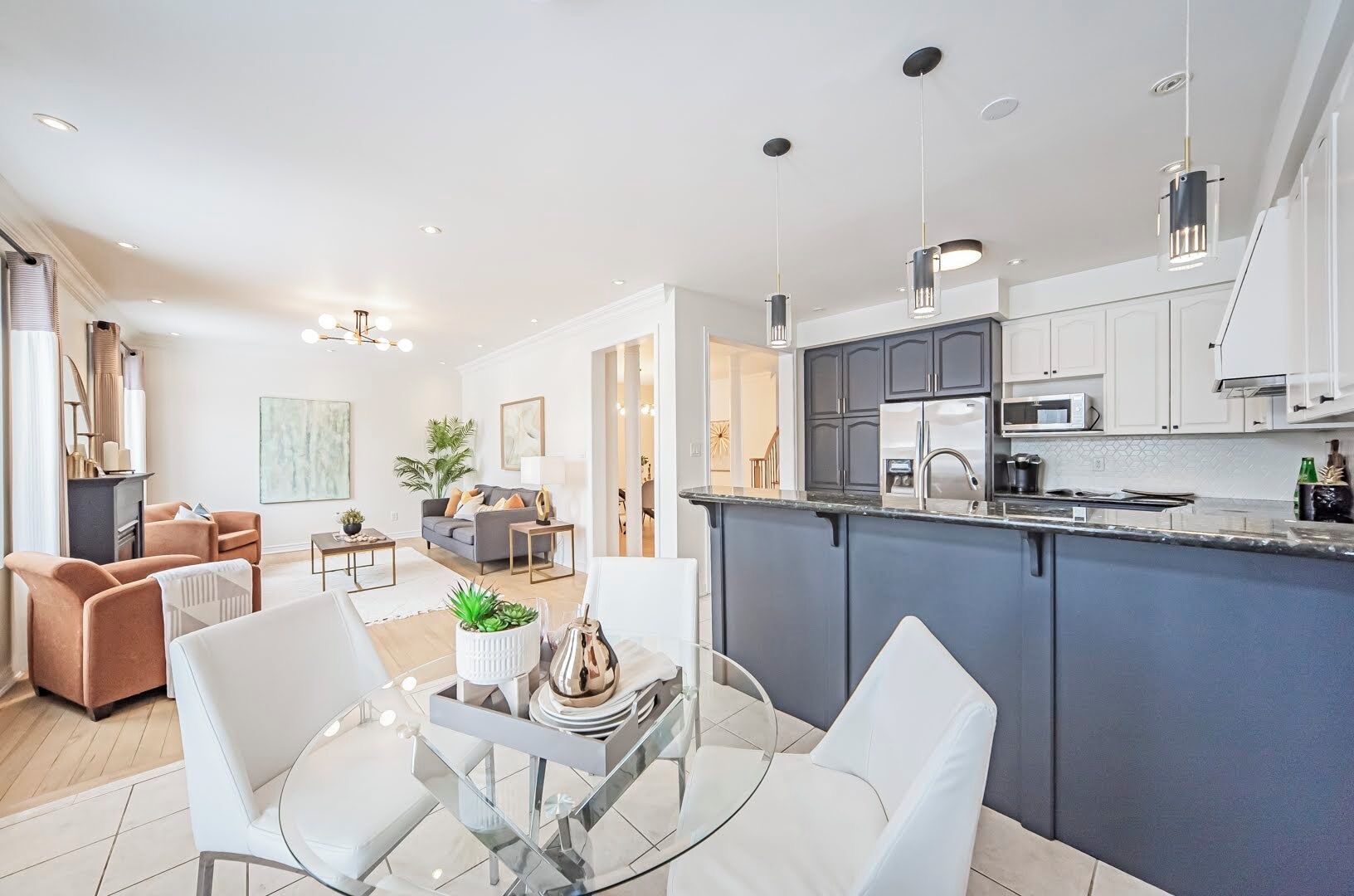 A modern kitchen with a central island, white cabinetry, and stainless steel appliances.