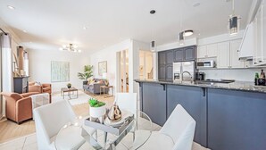 Une cuisine moderne dotée d’un îlot central, de meubles blancs et d’appareils électroménagers en acier inoxydable.