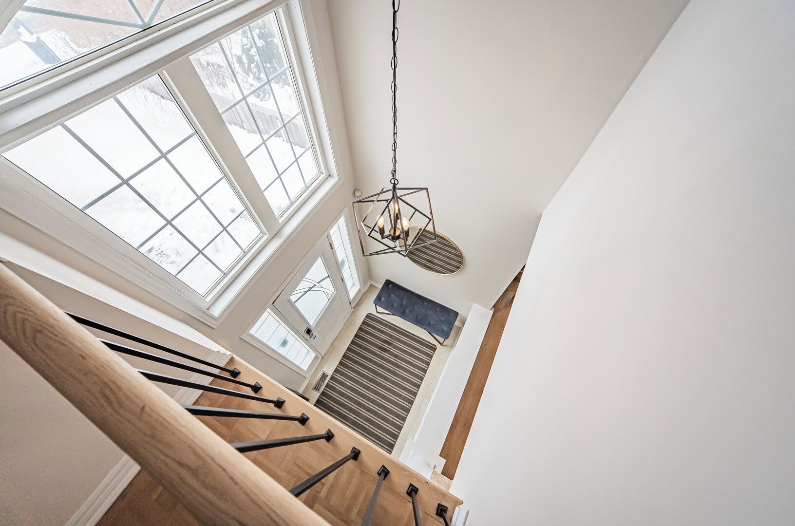 Una escalera con barandillas de madera y vista a una habitación con radiador y ventana.