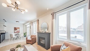 Un salon moderne doté d’une cheminée, de grandes fenêtres et d’un coin repas.