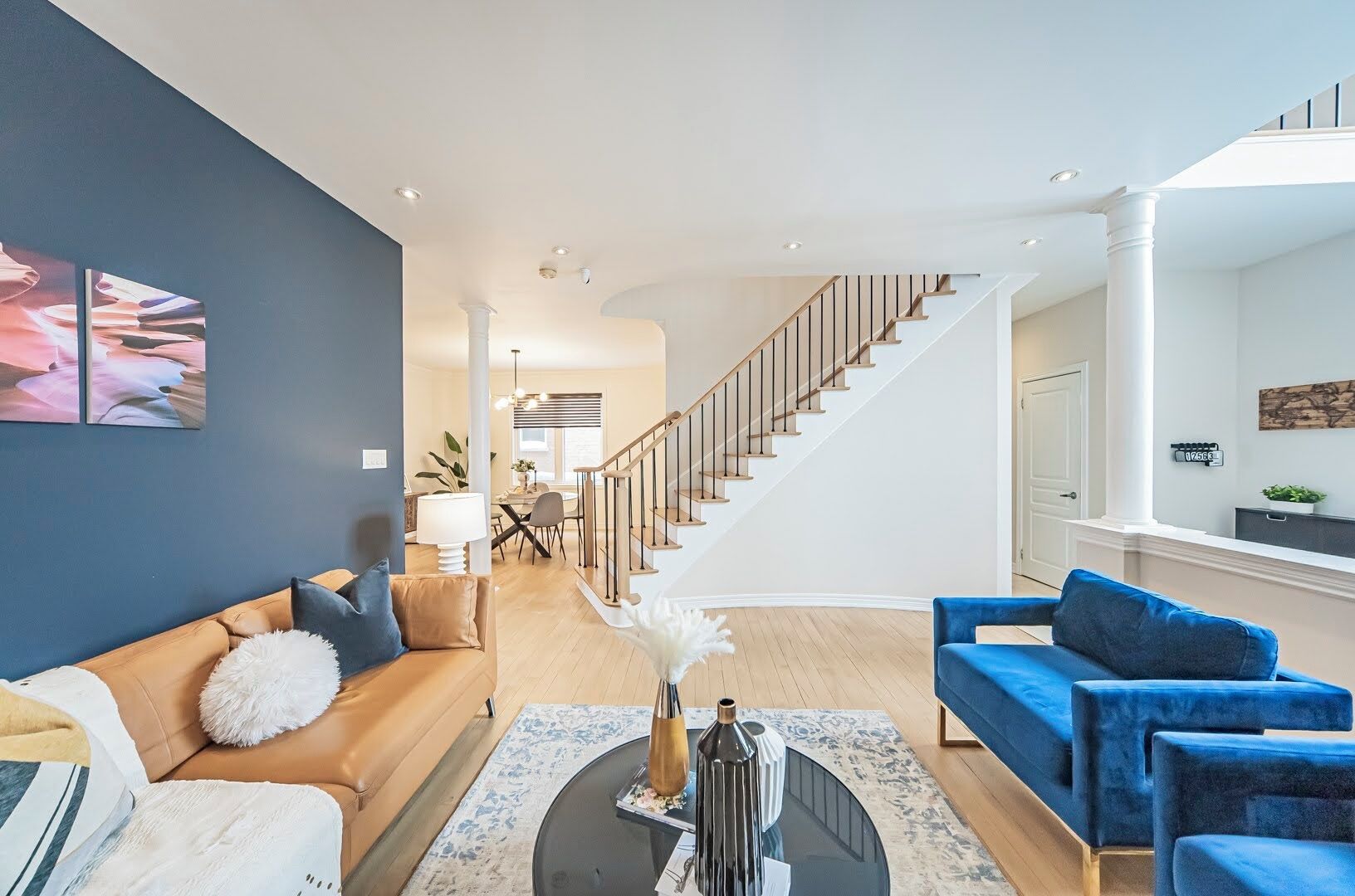 Een ruime woonkamer met een moderne trap, een eethoek en uitzicht op de stad.