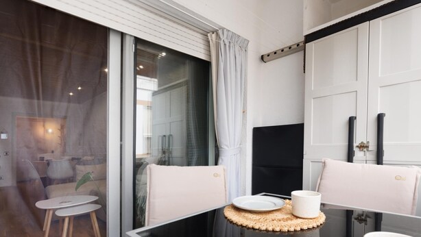 A modern room with a glass partition, a small round table with a plate and cup, and a chair with a cushion. - Quiet apartment Tossa de Mar (Tossa de Mar)
