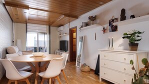 A modern living room with a wooden dining table, white chairs, a white cabinet, and a large mirror. - Quiet apartment Tossa de Mar (Tossa de Mar)