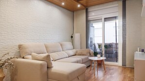 A modern living room with a beige sectional sofa, a small round table, and a white wall with a textured pattern. - Quiet apartment Tossa de Mar (Tossa de Mar)