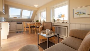 Un espace de vie compact comprenant un coin repas, un canapé et une table basse en verre.