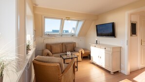 Un salon confortable avec un canapé, une table basse et un téléviseur fixé au mur.