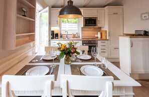 Una cucina moderna con mobili bianchi, un tavolo da pranzo per quattro persone e un'ampia finestra che lascia entrare la luce naturale.