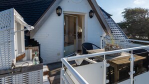 A small white building with a sloped roof, a door, and a window. There is a table and a chair outside. - Haus Sonnentraum, Whg. 2 - Sun-flooded 2-room apartment on approx. 60 m² for (Sylt)