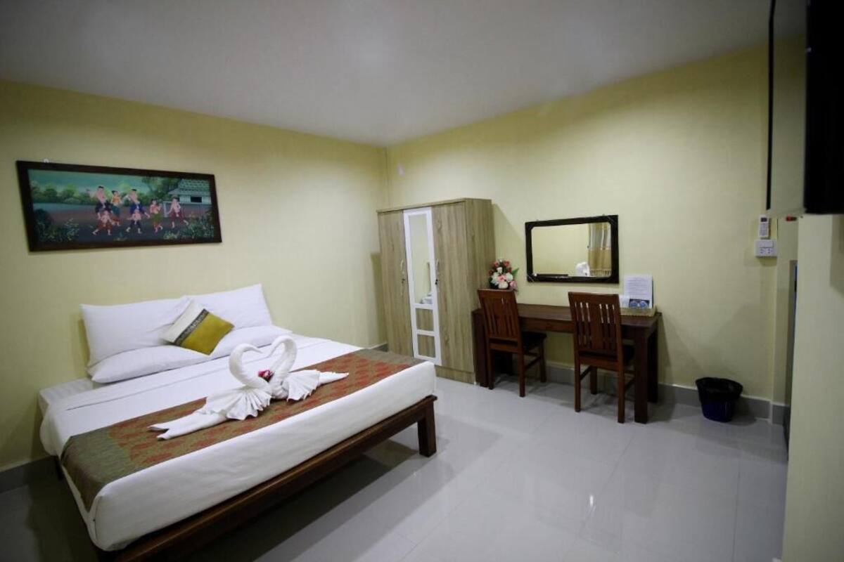 Quarto de hotel com cama, escrivaninha, cadeira, espelho e um quadro na parede.