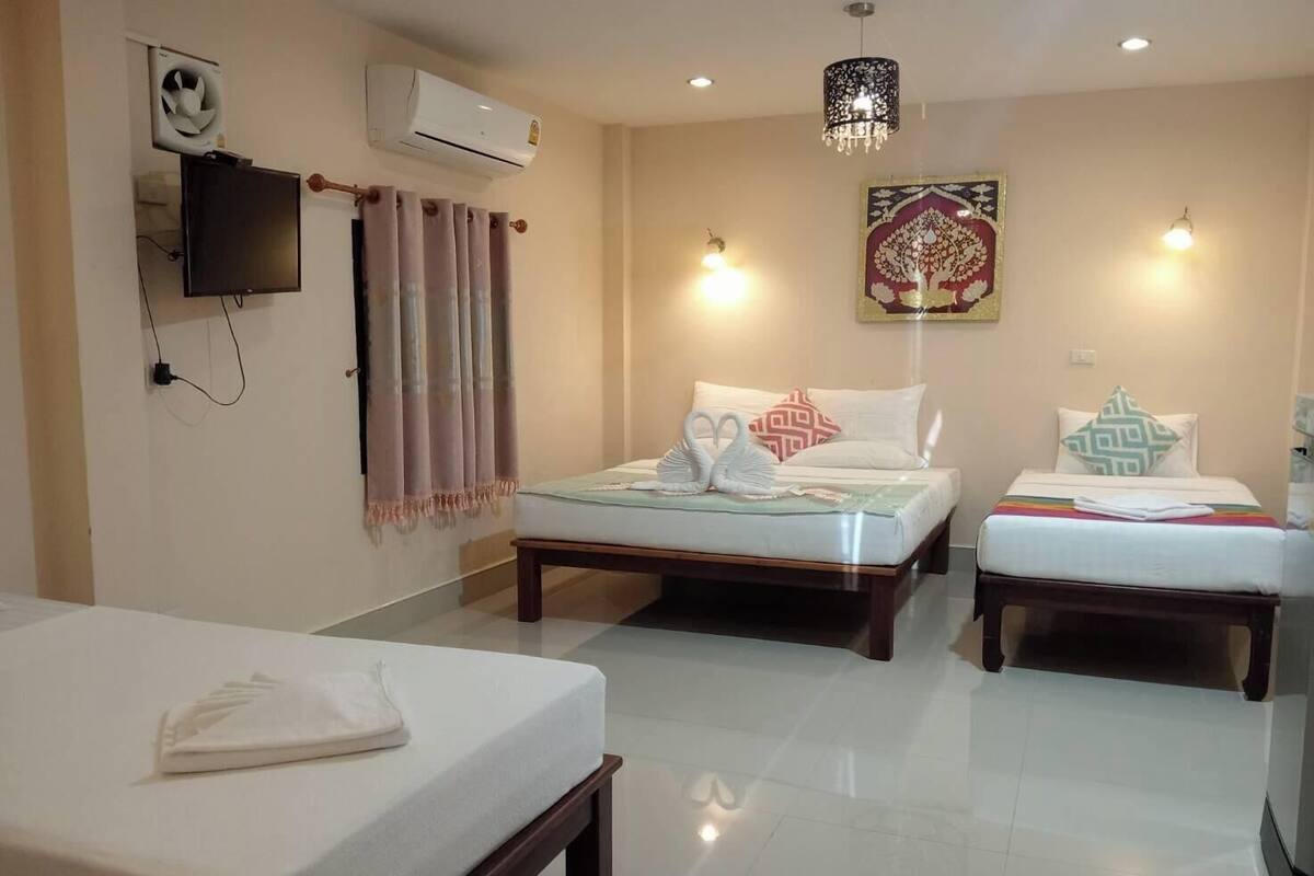 Quarto de hotel com duas camas, televisão, ar condicionado e lustre.