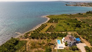 Une propriété située sur la côte, dotée d’une piscine, d’une grande maison et offrant une vue sur la mer.