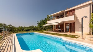 Une maison moderne à deux étages, dotée d’une piscine, d’un balcon et d’un jardin bien entretenu.