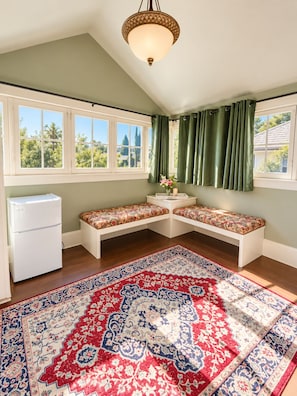 A room with a large window, a white refrigerator, a bench, a rug, and a ceiling light fixture. - Anne Haven Spacious Retreat DT Seattle (Seattle)