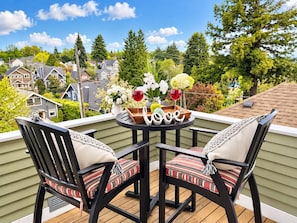 A balcony with two chairs, a table with a vase of flowers, and a glass of red wine. - Anne Haven Spacious Retreat DT Seattle (Seattle)