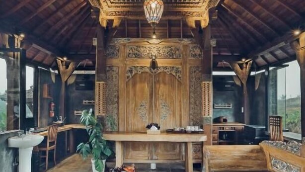 A traditional wooden interior with a central table, seating area, and a decorative ceiling.