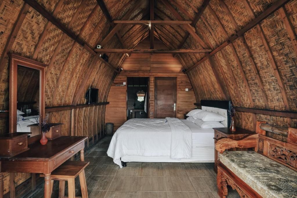 Un dormitorio con techo de madera, una cama, un escritorio y un banco.