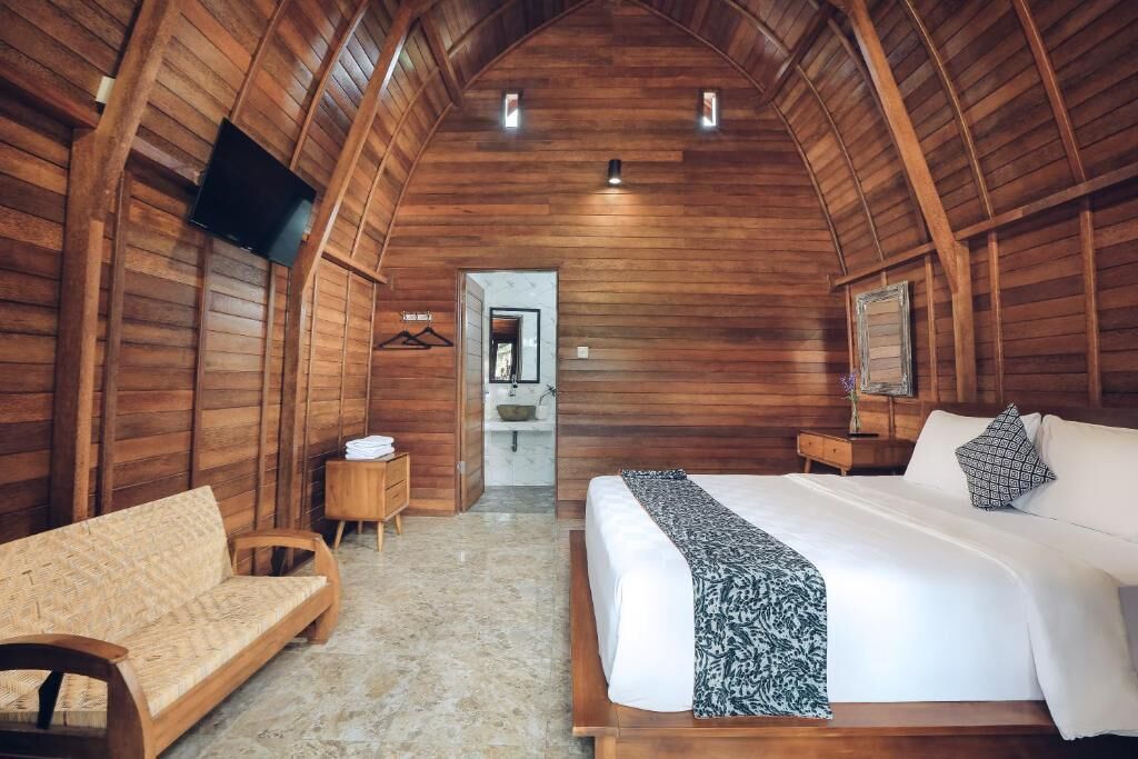 Una habitación acogedora tipo cabaña de madera con una cama, un sofá, un televisor y una mesita.