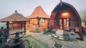 A rustic wooden building with a covered patio and a fountain.
